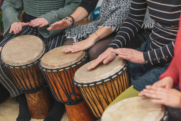 Women playing on a djembe drums during music therapy, drumming healing
