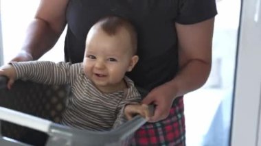 Anne ve bebek birlikte oynuyor, bebek çamaşır sepetinde sallanıyor, çocuk sevinci konsepti