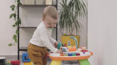 Emzik takan bebek renkli eğitici oyuncaklarla oynuyor.