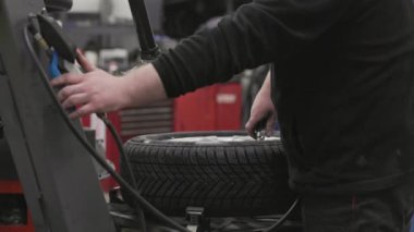 Tamirci garajda basınç göstergesi kullanarak araba lastiğini şişiriyor.