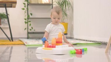 Bir aktivite masasında renkli blokları olan sevimli bebek, erken çocukluk gelişimini ve oyuncu öğrenimi sergiliyor.