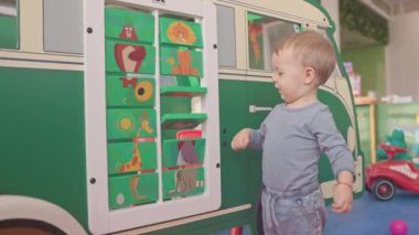 Meraklı çocuk interaktif bir tahtayla oynuyor, eğlenceli bir keşifte hayvan resimlerini ortaya çıkarıyor.