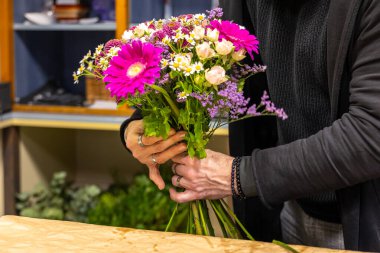 Çiçekçi çiçekçisinde pembe gerberalar, beyaz güller ve diğer renkli çiçeklerle güzel bir buket hazırlıyor.