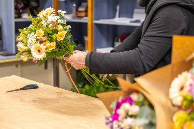 Çiçekçi çiçekçisinde renkli bir çiçek buketi hazırlıyor.