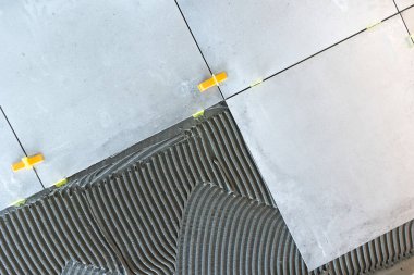 Profesyonel tiler seramik fayansları çimento yapıştırıcısına yerleştiriyor, döşeme sistemi kullanıyor