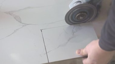 Açı öğütücüsünü kullanarak mermer kiremit kesen inşaat işçisi