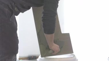 İnşaat işçisi, beyaz arka planda izole edilmiş bir mala çimento döküyor.