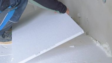 İnşaat işçisi stiroköpük yalıtım panellerini yerleştiriyor ve kesiyor, termal yalıtım işi yapıyor.