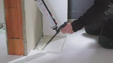 İnşaat işçisi poliüretan uyguluyor. Zemin yalıtım panellerine köpük yayıyor.