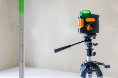 Boş bir odadaki inşaat ya da yenileme projesi sırasında yeşil ışını cetvel üzerine yansıtan lazer seviyesi