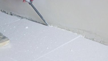 İnşaat işçisi, sıcak hava tabancasıyla duvardaki polistiren izolasyonu kaldırıyor.