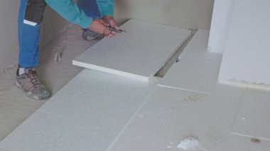 Yerdeki beyaz strafor yalıtım panellerini yerleştiren ve kesen işçiler