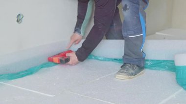Profesyonel müteahhit beyaz strafor yalıtım panelleri üzerine turkuaz buhar bariyeri döşeyerek film yapıyor.