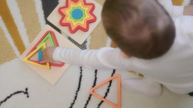 Bebek renkli ahşap oyuncaklarla oynar, öğrenme şekilleri ve renkleri
