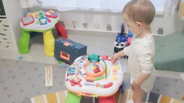 Bebek çocuk renkli oyun alanında interaktif öğrenme oyuncağını keşfediyor