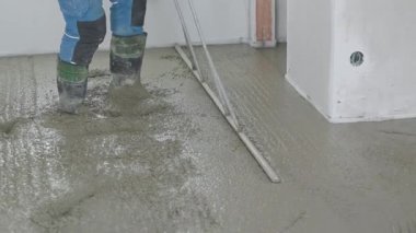 Islak beton yüzeyini boğa yüzeyi kullanarak düzleştiren inşaat işçisi
