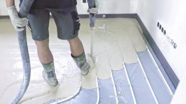 İnşaat işçisi zemini pürüzsüz bir şekilde ısıtmak için beton karışımını döker.