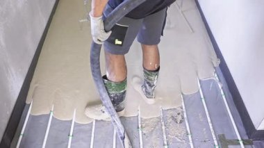 Profesyonel müteahhit, zemini pürüzsüz hale getirmek ve alt kattaki ısıtma borularını kapatmak için sıvı tornavida kullanır.