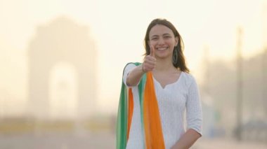 Confident Indian girl doing Thumbs up at India gate Delhi in an Indian traditional wear