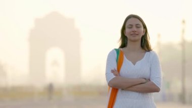 Indian girl standing crossed hands at India gate in an Indian traditional wear