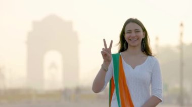 Indian girl politician showing Victory sign at Indian gate in an Indian ethnic outfit