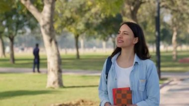 Happy Indian college girl roaming in the college campus with bag and notebooks