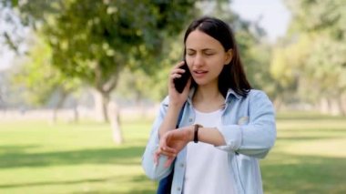 Indian girl waiting for someone and trying to reach him or her through phone call