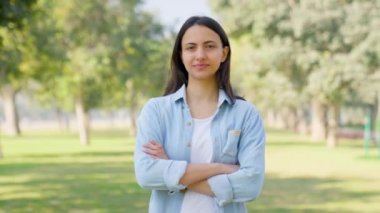 Confident Indian businesswoman standing crossed hand in a park