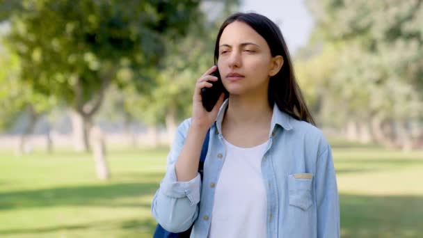 一个严肃的印度女孩在大白天打电话到公园里 — 图库视频影像