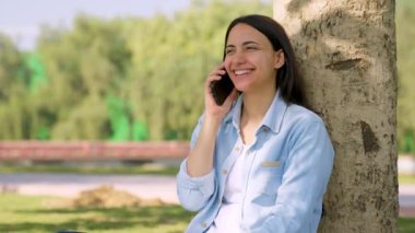 Happy Indian girl talking to someone on mobile phone in a park