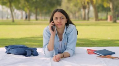 Indian college girl talking on phone in a park