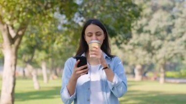 Indian girl drinking coffee at a park in a daylight