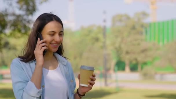 Onnellinen Intialainen Tyttö Puhuu Puhelimessa Kävellessään Puistossa — kuvapankkivideo