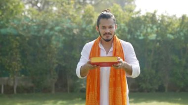 Indian man offering sweet box to the camera