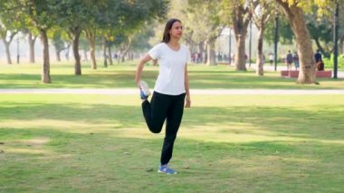 Indian woman doing leg stretching exercise in a park in morning