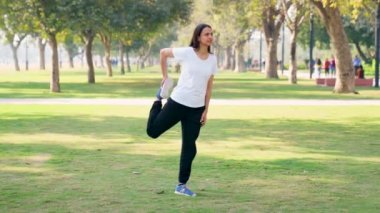 Indian woman stretching her legs and doing warm up in a park in morning