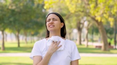 Indian woman wiping her sweat using a towel after a workout in a park in morning