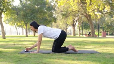 Indian girl learning yoga from Internet in a park in morning time