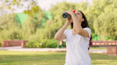 Indian girl drinking water from bottle in a park in morning time