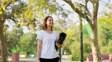 Indian woman walking with Yoga mat in a park in morning time