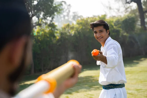 Young Indian men playing Holi with water gun