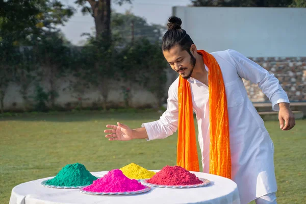 Indian man picks up pink gulal color from a plate