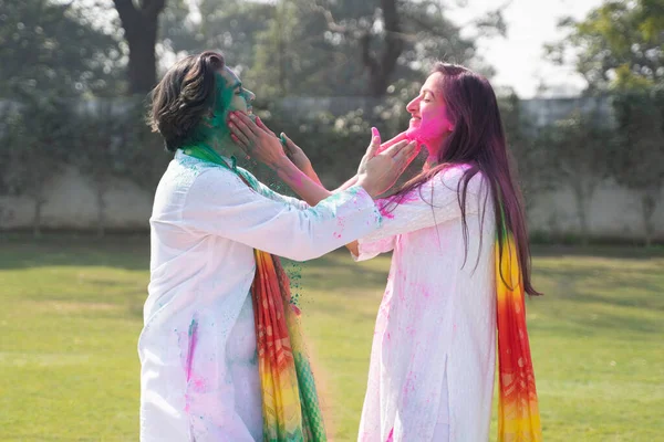 Cute Indian couple putting Holi colors at each other faces