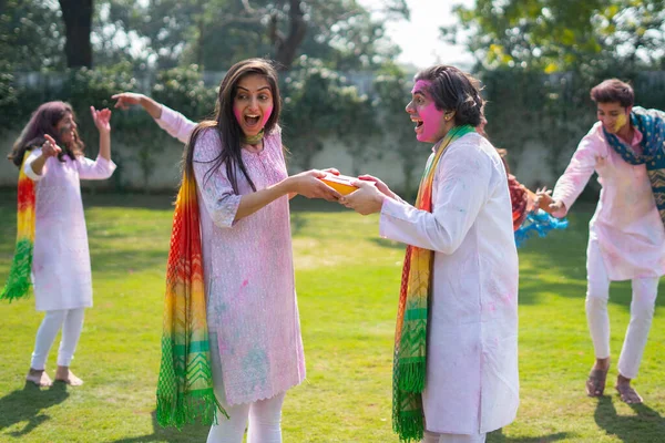 Indian man giving a gift to his wife at a Holi party