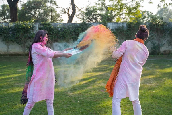 Indian woman throwing Gulal color at her partner in a Holi festival
