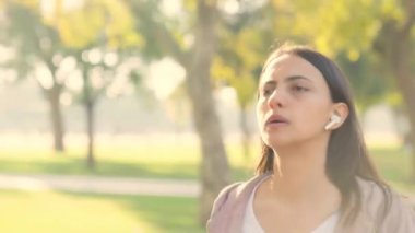 Indian young woman running with earphones on in a park in morning time