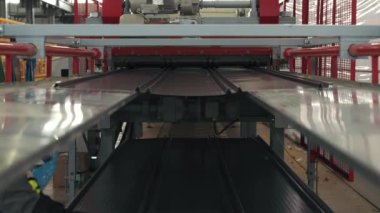 Modern metal fabrikasında metal ya da çelik levha oluşturma makinesi. Çatı Üretim Süreci. Ekipmanların çalışması yavaş çekimde gösterilir