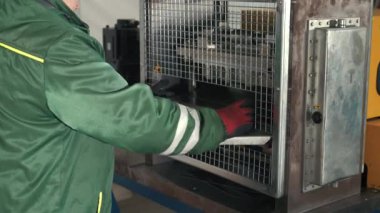 Metal işçiliği yapan bir makine, bir metal levhayı dikdörtgen şeklinde keser. Eldiven giyen bir işçi ise kuru sıkı monte eder. Otomatik Metal Katlama ve Bükme Makinesi. Üretim süreci. Hassas Makine. Kapat.