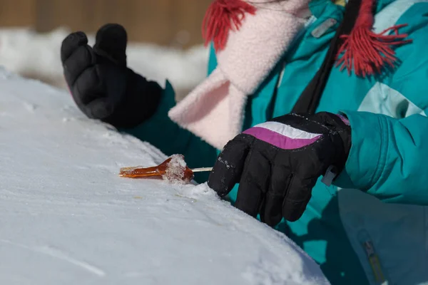 在加拿大魁北克市 一个女孩在雪地上翻滚热枫树糖浆 — 图库照片