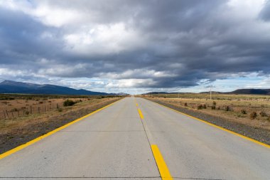 Karanlık bulutlu bir günde Şili 'deki Atacama Çölü' nü geçen sarı çizgilerle dolu uzun düz bir yol.. 